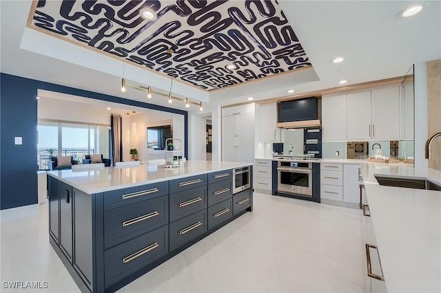 kitchen with white cabinets, stainless steel oven, sink, and a tray ceiling