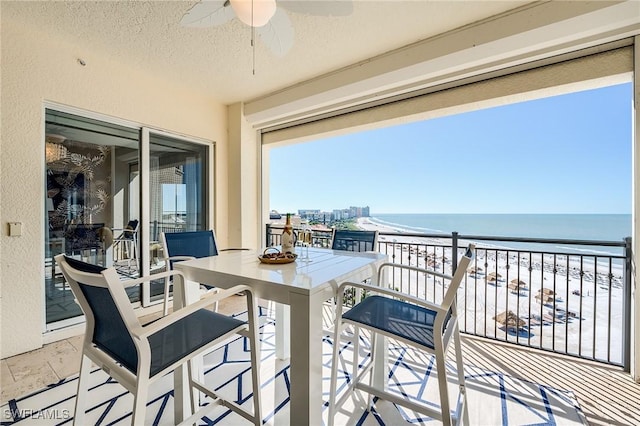 balcony featuring ceiling fan, a water view, and a beach view