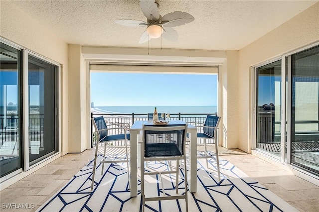 sunroom featuring ceiling fan and a water view