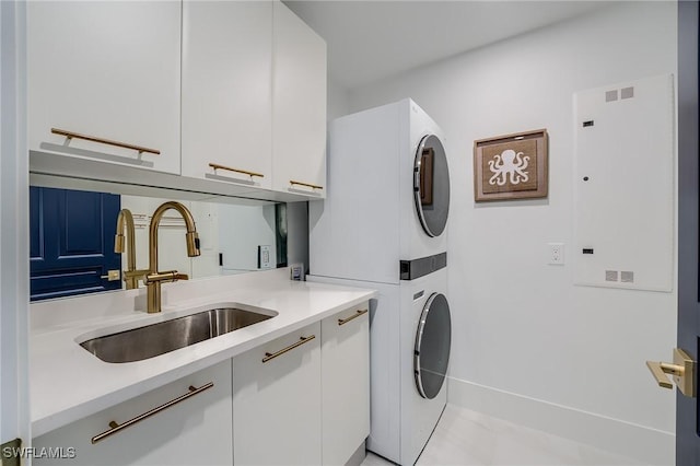 washroom featuring sink, cabinets, and stacked washer and clothes dryer