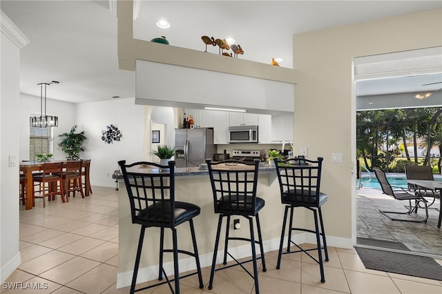 kitchen featuring a kitchen bar, white cabinetry, kitchen peninsula, and appliances with stainless steel finishes