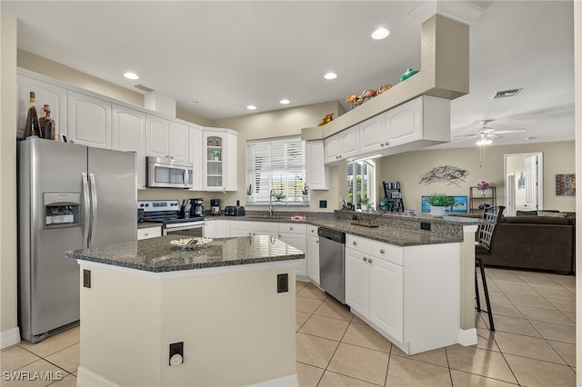 kitchen featuring white cabinetry, a kitchen island, a kitchen bar, kitchen peninsula, and stainless steel appliances