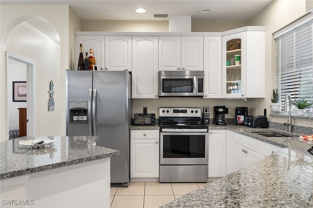 kitchen featuring appliances with stainless steel finishes, white cabinetry, glass insert cabinets, and light stone countertops