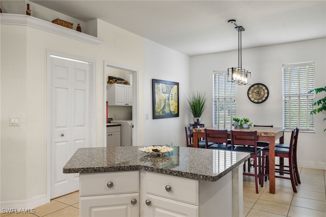 kitchen featuring white cabinetry, hanging light fixtures, a kitchen island, an inviting chandelier, and light tile patterned flooring