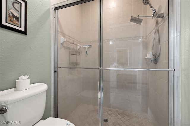 bathroom featuring a shower with shower door and toilet