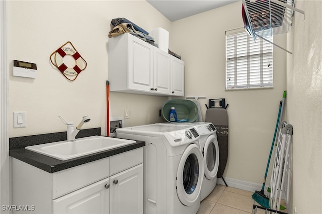 clothes washing area with light tile patterned flooring, cabinets, sink, and washing machine and clothes dryer