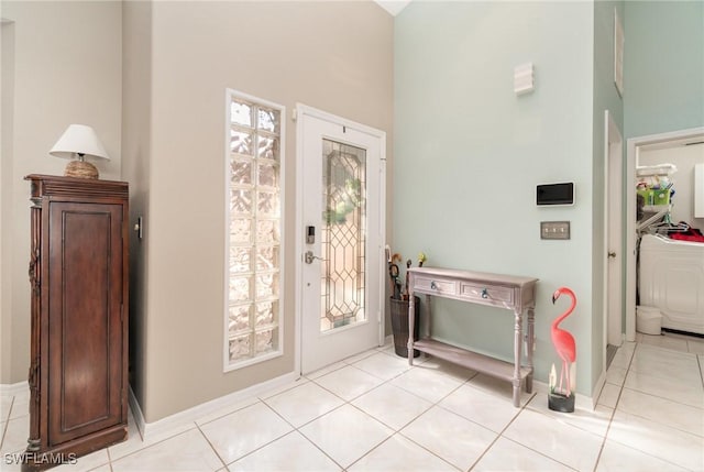 foyer entrance featuring light tile patterned floors, baseboards, and washer / clothes dryer