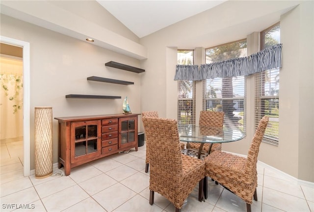 dining space with vaulted ceiling, baseboards, and light tile patterned floors