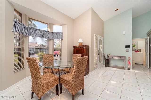 dining space with high vaulted ceiling and light tile patterned flooring