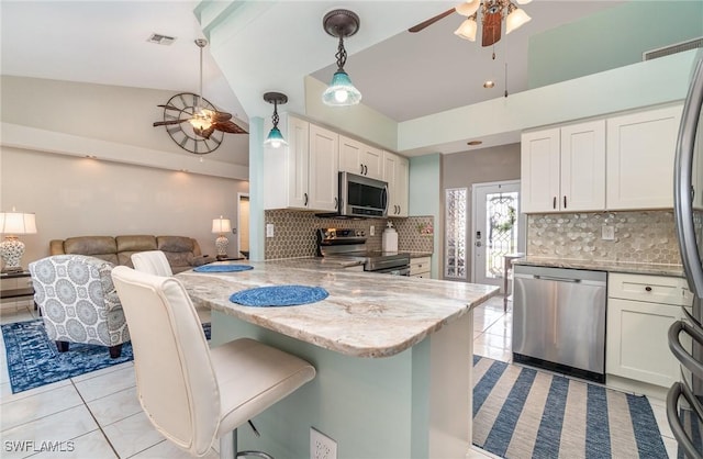 kitchen with hanging light fixtures, white cabinetry, a kitchen bar, kitchen peninsula, and stainless steel appliances