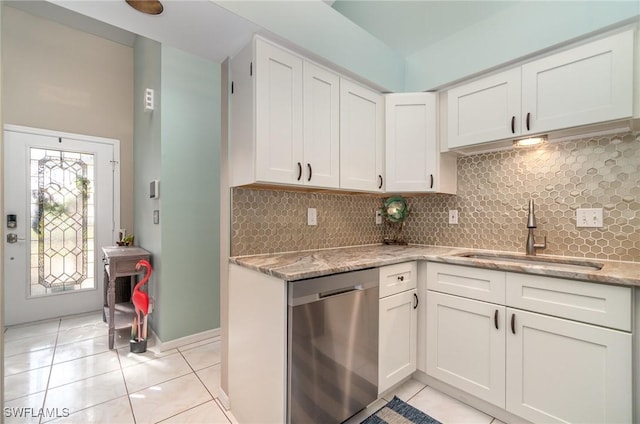 kitchen with white cabinetry, dishwasher, light stone countertops, sink, and light tile patterned floors