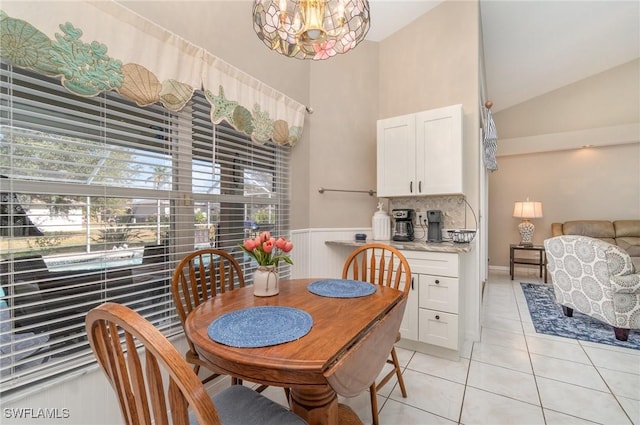 dining space with vaulted ceiling, light tile patterned floors, and a chandelier