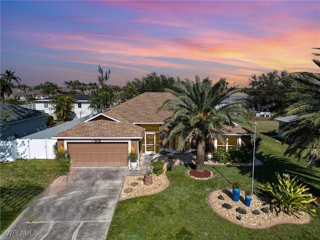 view of front facade with a garage, fence, concrete driveway, and a yard