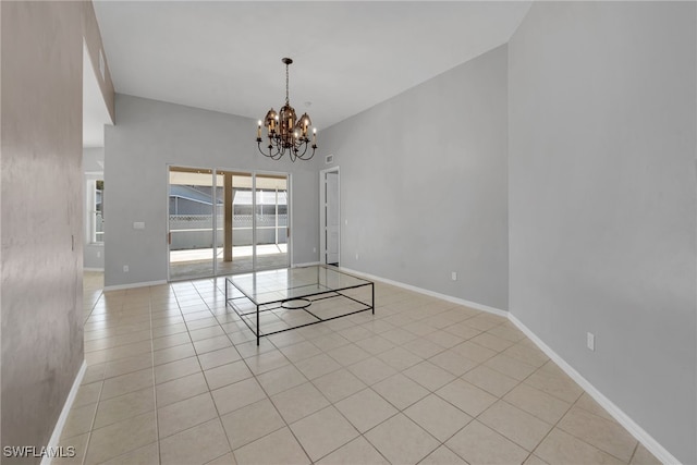 empty room with light tile patterned floors, a towering ceiling, and an inviting chandelier