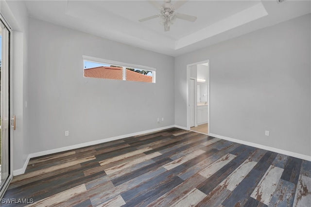 spare room featuring ceiling fan, dark hardwood / wood-style flooring, and a tray ceiling