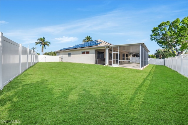 rear view of property featuring solar panels, a lawn, and a sunroom