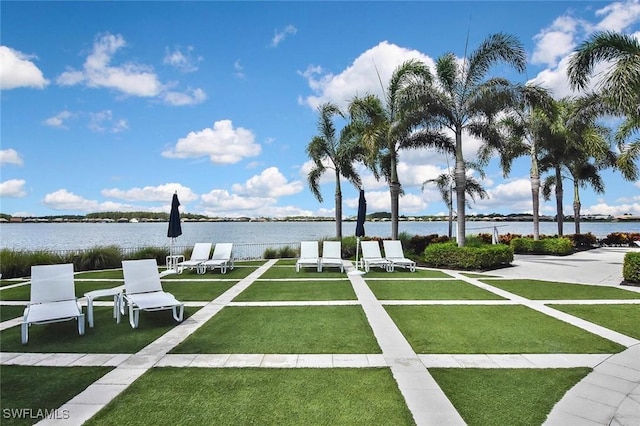 view of property's community with a water view and a lawn