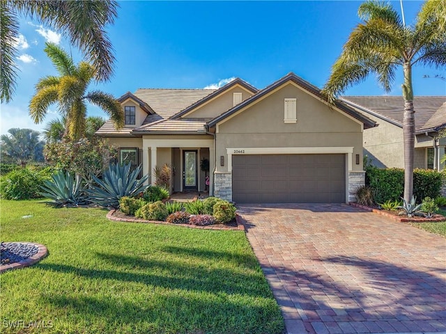 20462 Misty Woods Ct, Estero, FL 33928 - traditional-style house with stucco siding, an attached garage, a front yard, decorative driveway, and stone siding