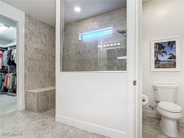 bathroom featuring a tile shower and toilet