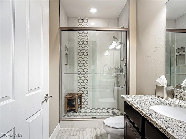 bathroom featuring toilet, vanity, and walk in shower