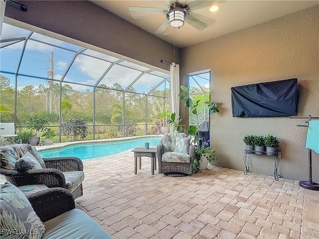 view of swimming pool with a patio, glass enclosure, and ceiling fan