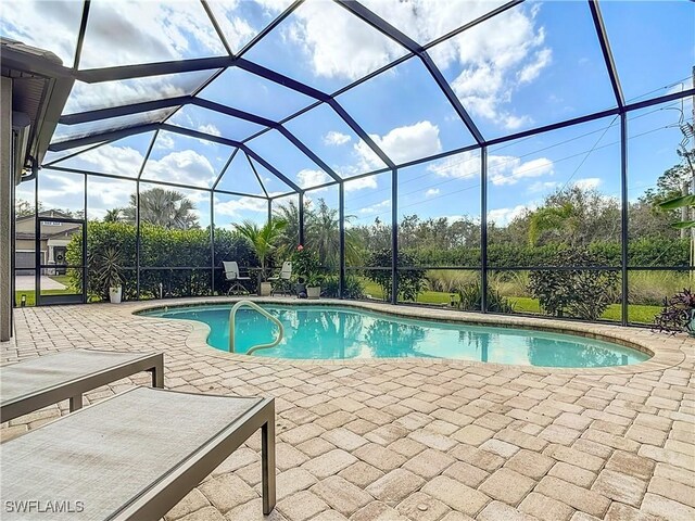 view of swimming pool with glass enclosure and a patio area