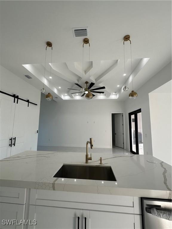 kitchen with decorative light fixtures, light stone counters, and sink