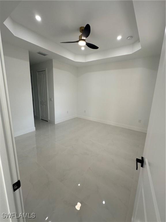 spare room featuring a raised ceiling and ceiling fan