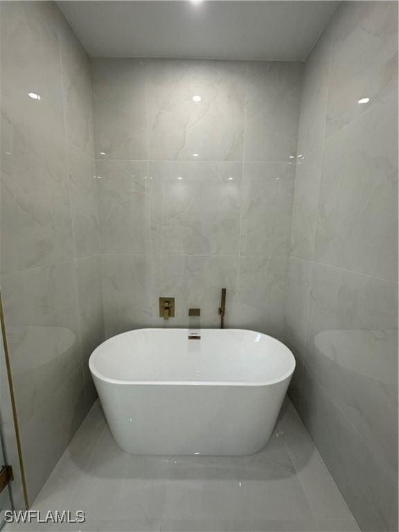 bathroom featuring a washtub and tile walls