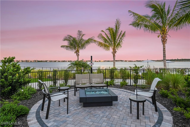 patio terrace at dusk with a water view and an outdoor living space with a fire pit