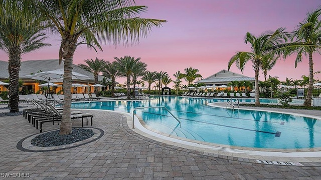 pool at dusk featuring a patio area