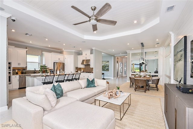 living room with ceiling fan and a tray ceiling