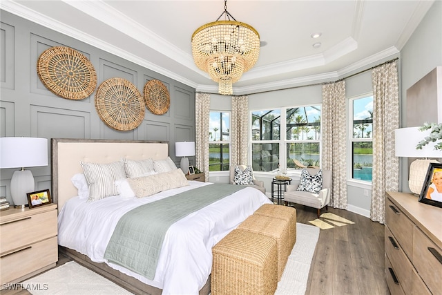 bedroom featuring a raised ceiling, dark hardwood / wood-style flooring, an inviting chandelier, and ornamental molding