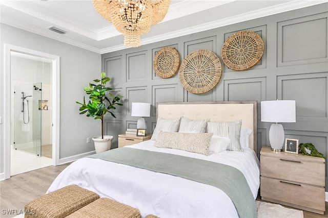 bedroom featuring ensuite bathroom, light hardwood / wood-style flooring, crown molding, and a chandelier