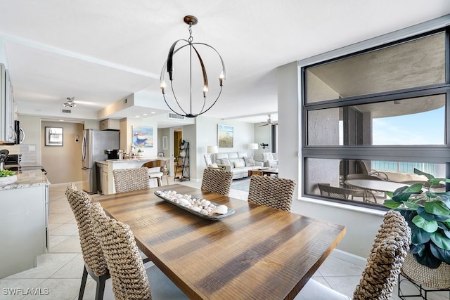 tiled dining space with ceiling fan with notable chandelier