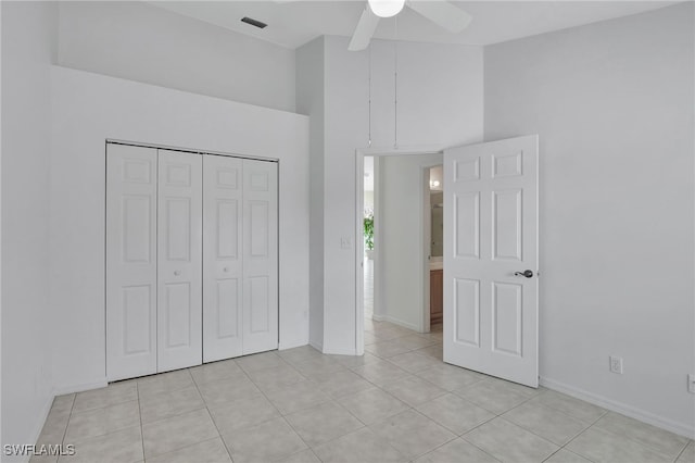 unfurnished bedroom featuring a high ceiling, light tile patterned floors, ceiling fan, and a closet