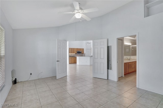 tiled spare room with sink, high vaulted ceiling, and ceiling fan