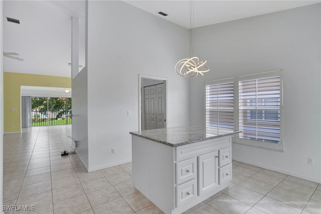 kitchen with white cabinetry, light tile patterned floors, decorative light fixtures, and stone countertops