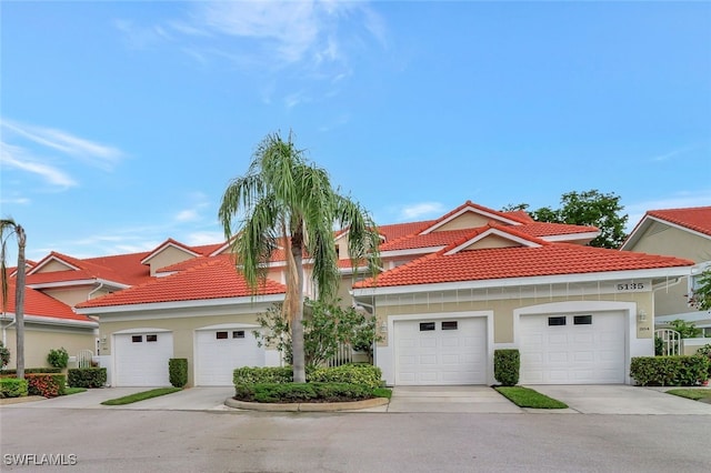 view of front of home with a garage, a tile roof, and stucco siding