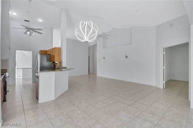 kitchen with pendant lighting, high vaulted ceiling, ceiling fan with notable chandelier, and light tile patterned floors