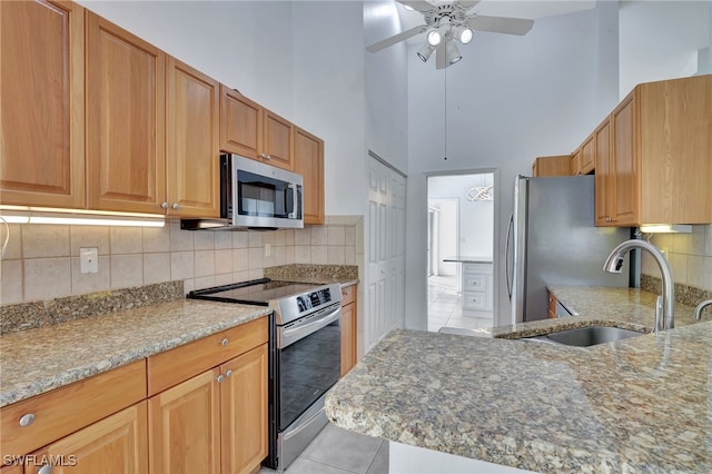 kitchen with sink, light tile patterned floors, backsplash, stainless steel appliances, and light stone countertops