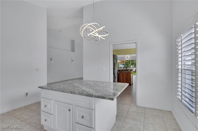 kitchen featuring a chandelier, light tile patterned flooring, white cabinetry, hanging light fixtures, and freestanding refrigerator