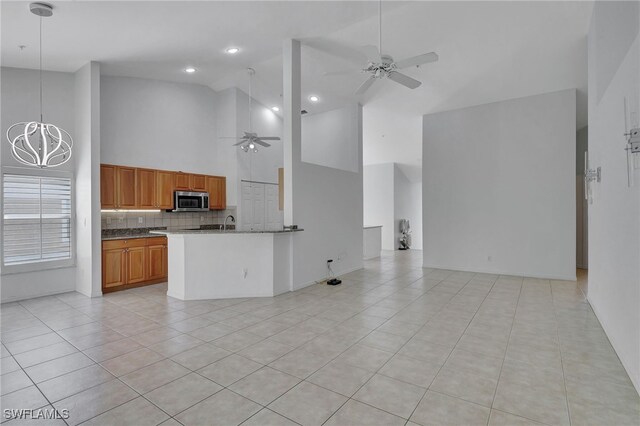 kitchen featuring pendant lighting, ceiling fan with notable chandelier, backsplash, light tile patterned floors, and kitchen peninsula