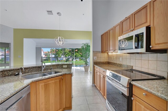 kitchen with appliances with stainless steel finishes, sink, backsplash, hanging light fixtures, and light stone counters