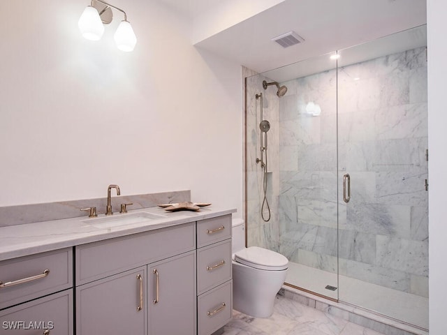 bathroom with toilet, vanity, and a shower with shower door