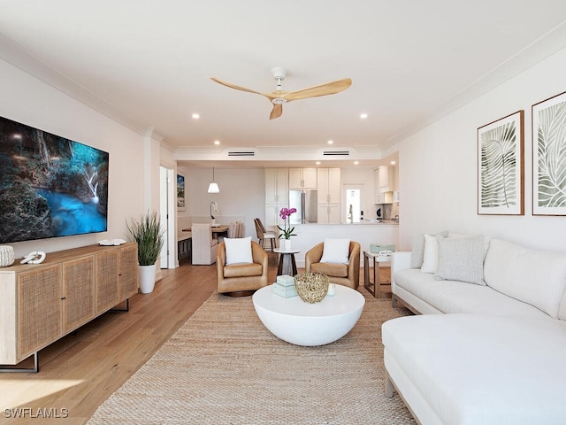 living room featuring crown molding, ceiling fan, and light hardwood / wood-style flooring