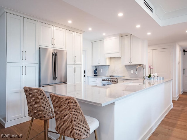 kitchen featuring appliances with stainless steel finishes, a kitchen bar, white cabinets, and light hardwood / wood-style floors