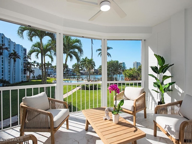 sunroom / solarium with ceiling fan and a water view