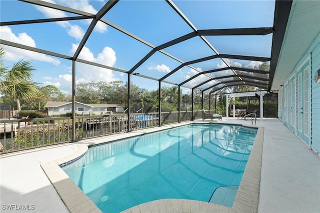 view of swimming pool with glass enclosure, a water view, and a patio