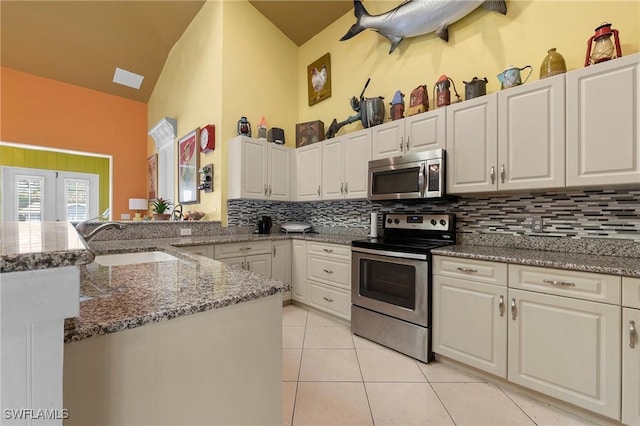 kitchen with decorative backsplash, appliances with stainless steel finishes, dark stone counters, white cabinets, and light tile patterned flooring